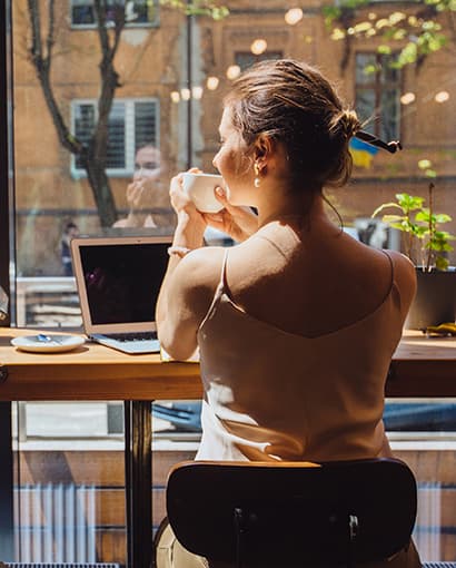 Women drinking coffee while using ECCU online banking at coffee shop